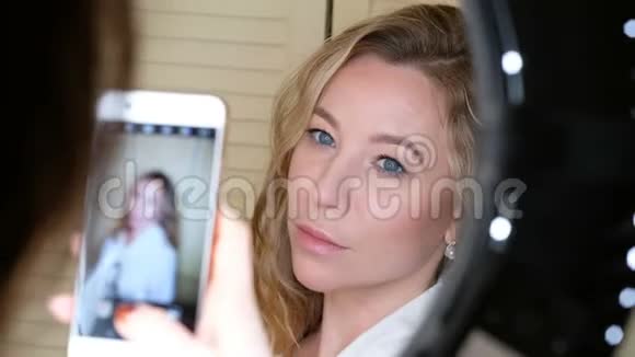一位女士用智能手机拍下了一个漂亮女孩的照片上面挂着一盏带环的灯视频的预览图