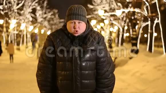 一个年轻的成年男子在冬季城市街道他冻僵了搓着手冻得发抖视频的预览图