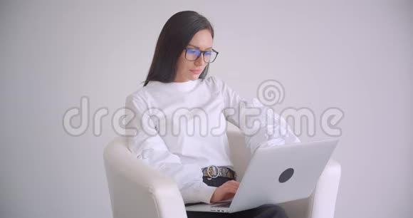 年轻漂亮的白种人女商人戴着眼镜用手提电脑看着镜头开心地笑着的特写照片视频的预览图