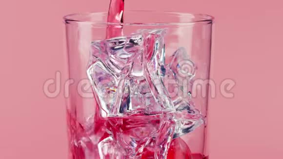 将红色软饮料倒入带有粉红色背景的冰块的玻璃杯中慢镜头对准红色视频的预览图