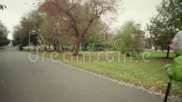穿绿色连体衣的孩子在公园里骑摩托车视频的预览图