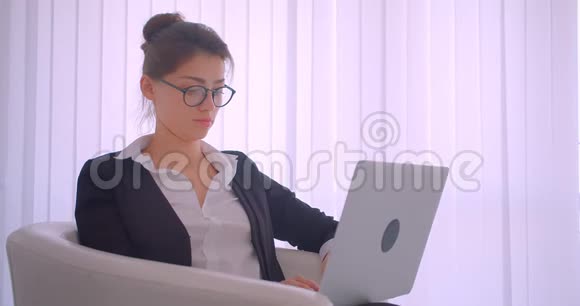 一位年轻漂亮的高加索女商人在一间白色房间里用笔记本电脑拍摄特写镜头视频的预览图