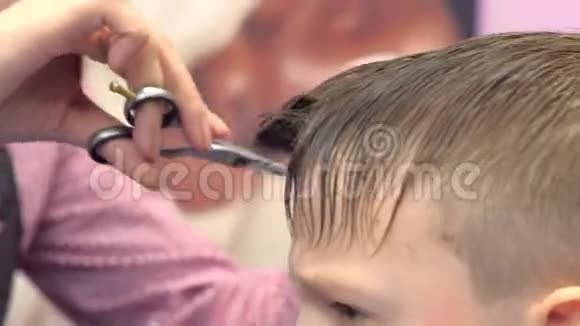 理发师用剪刀在男孩头上剪刘海发型师双手特写侧视视频的预览图