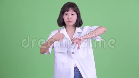 困惑的亚洲女商人在竖起大拇指和竖起大拇指之间做出选择视频的预览图