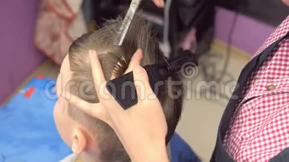 理发师用剪刀在男孩头上磨头发俯视图造型师手特写视频的预览图