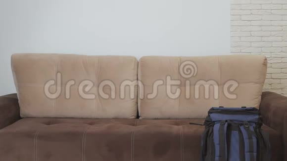一个腰酸背痛的男人走到沙发上坐在沙发上拿起电话打电话视频的预览图