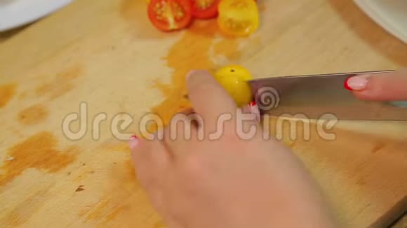 一个女人正在用一把刀在木板上切一个黄色和红色的樱桃番茄时光飞逝视频的预览图