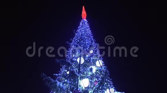 圣诞树顶上装饰着花环和灯光夜晚发光新年前夕在城市的冬天概念视频的预览图
