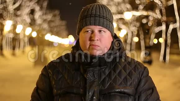 冬天寒冷的夜晚胖子在户外咀嚼的肖像视频的预览图