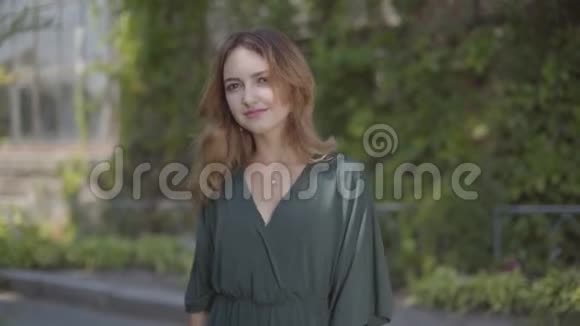 美丽的年轻女子站在夏季公园里看着相机微笑的肖像概念视频的预览图