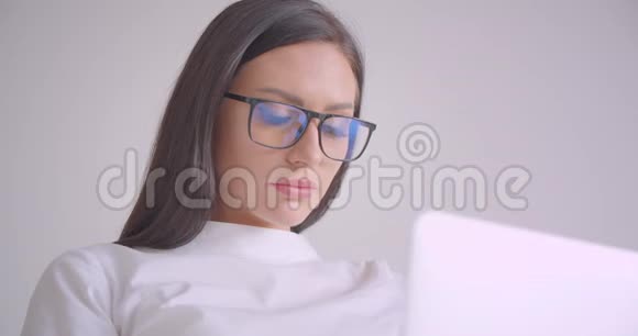 年轻漂亮的白种人女商人戴着眼镜看着镜头开心地用笔记本电脑笑着特写照片视频的预览图
