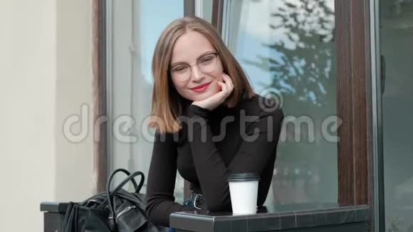 漂亮的红发年轻女子短发四面戴着眼镜和棕色高领毛衣坐在上面视频的预览图