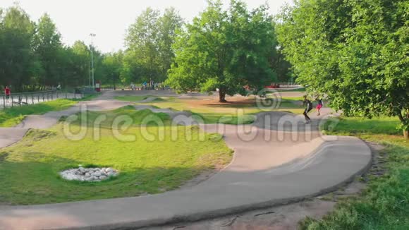 现代绿色公园两个年轻人在波浪形的道路上滑板视频的预览图