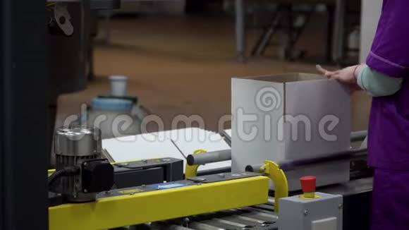 一位工厂女工正在铺设新的箱子并把它们放在传送带上视频的预览图