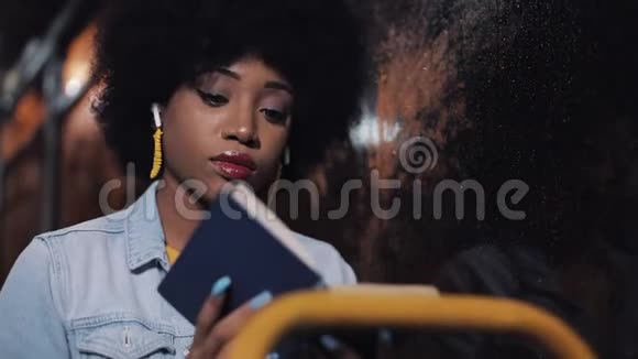 快乐的非裔美国妇女乘坐公共交通工具读完书后看着窗外合上书视频的预览图