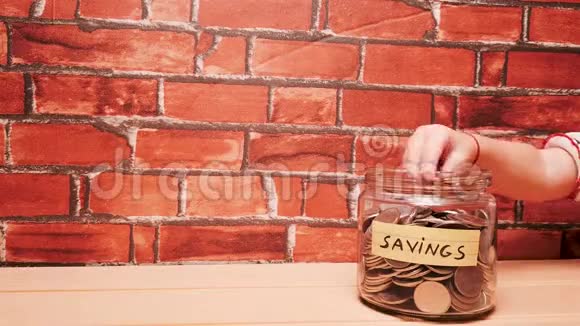 一只小婴儿手把钱币放进钱箱存钱罐里孩子为未来的概念省钱视频的预览图