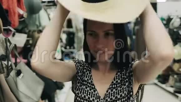 积极的女孩在购物中心选择了一个夏季配件近景有魅力的女人戴着时髦的帽子视频的预览图