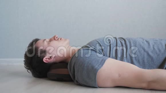 疲惫的家伙躺在地板上用电动按摩枕头视频的预览图