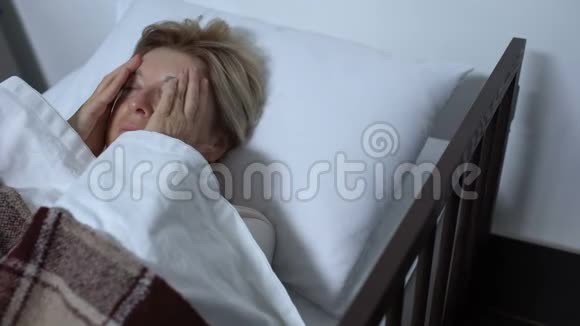 老年女性患者按摩太阳穴在病床上严重偏头痛视频的预览图