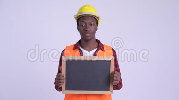年轻快乐的非洲建筑工人拿着黑板看上去很惊讶视频的预览图