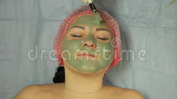 一位戴手套的男性美容师用特殊的刷子在客户的脸上涂上一层泥视频的预览图