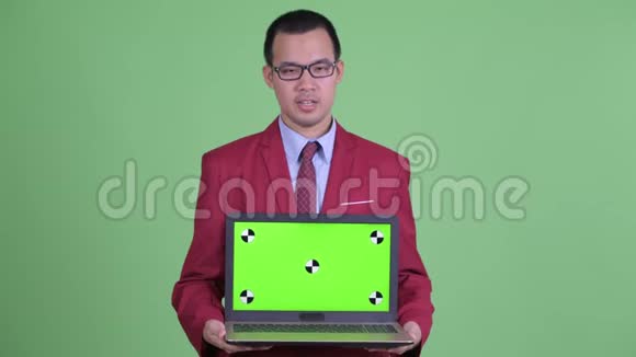 快乐的亚洲商人一边说话一边展示笔记本电脑视频的预览图
