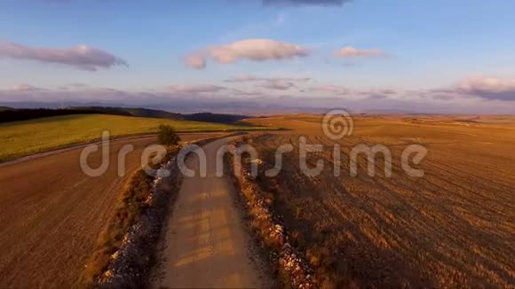 空中鸟瞰镜头飞行在美丽的乡村景观的乡村道路上日落视频的预览图