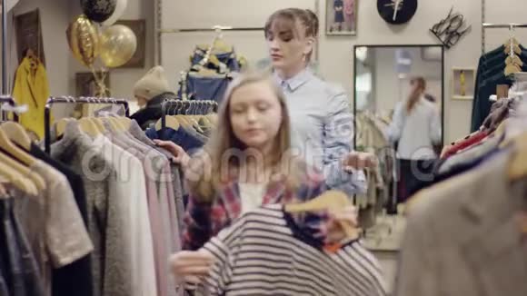 年轻漂亮的女售货员带着一件t恤走了而她的女客户却在找新衣服视频的预览图