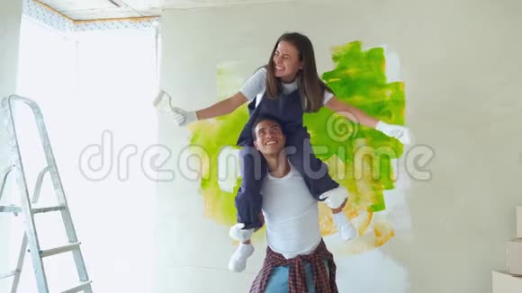 夫妻俩正在玩着重新装修他们的新公寓快乐的女孩坐在男人的肩膀上画墙视频的预览图