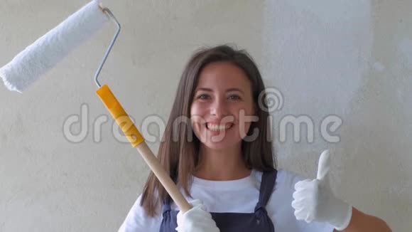 一个年轻女孩做修理那个拿着滚筒的女孩在墙上画画女孩修理和微笑绘画视频的预览图