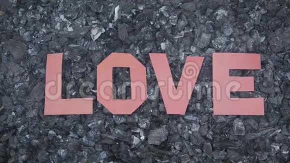 在炎热的烟煤上铭文的爱是由纸上剪下的字母制成的视频的预览图