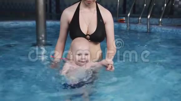 小幼儿不怕在健身中心的水池里学游泳妈妈教儿子在游泳池里游泳视频的预览图