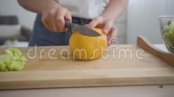 一位年轻女子用锋利的刀在厨房的桌子上切着大黄番茄健康观念视频的预览图