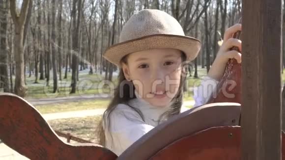 可爱的小女孩在春天公园的操场上掌着船肖像快关门4K25fps视频的预览图