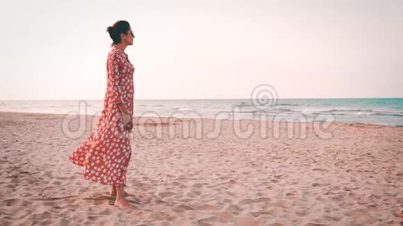 日落时分一位身穿红裙微笑着望着地中海的美丽女子慢镜头视频的预览图