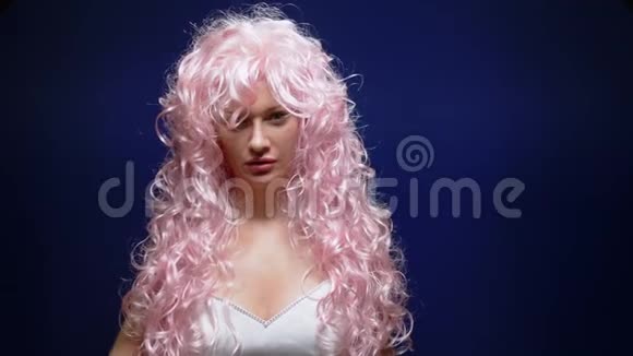 一个黑色背景上有粉红色头发的漂亮女孩摘下假发留着光头视频的预览图
