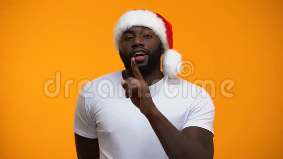 黑色圣诞老人展示沉默标志和眨眼手持礼物秘密圣诞派对视频的预览图