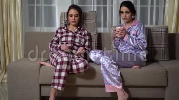 两个双胞胎姐妹晚上在舒适的客厅里放松看电影做黄瓜眼罩和视频的预览图