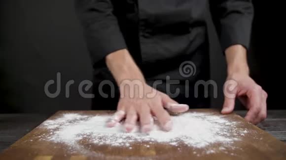 厨师在黑色背景的木桌上铺面粉视频的预览图