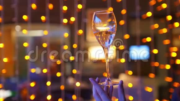 一个女人手拿着一杯香槟在橙色灯光的背景下视频的预览图