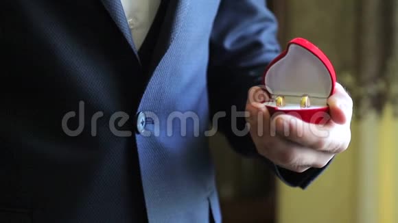 一个拿着结婚戒指的盒子的男人视频的预览图