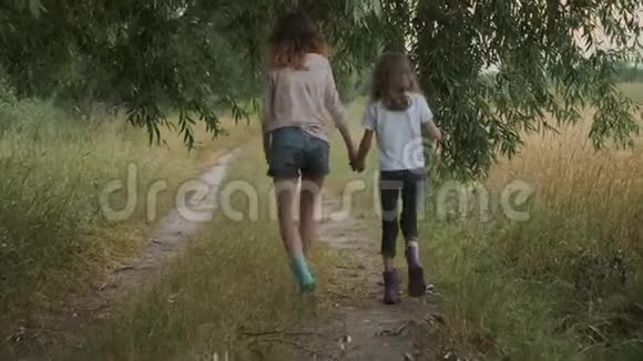 两个快乐的女孩姐妹在雨后穿着脏衣服牵着手散步视频的预览图