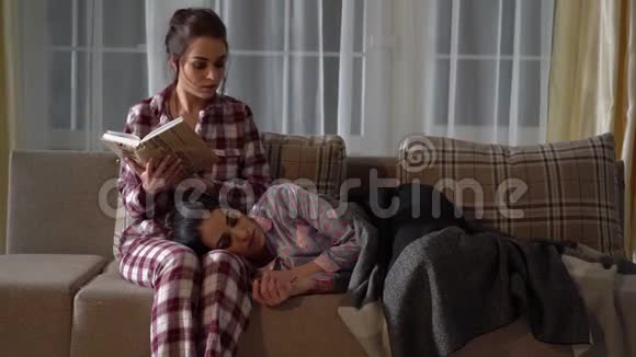 两个漂亮的双胞胎晚上穿着睡衣在房间里一个女孩正在看书而她妹妹正在睡觉视频的预览图
