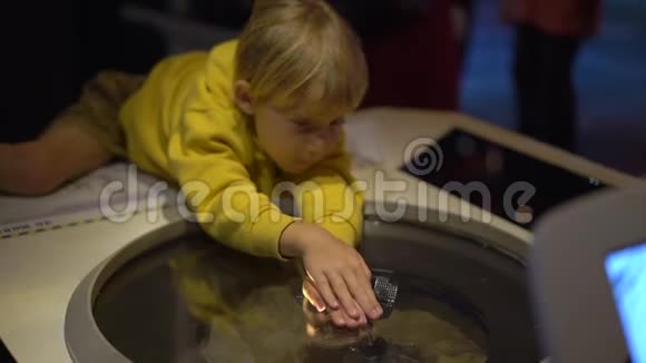 一个小男孩参观儿童科学博物馆的慢镜头他试图捕捉到一个全息投影视频的预览图