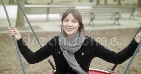 快乐活泼的女人在操场上坐在秋千上玩得很开心视频的预览图