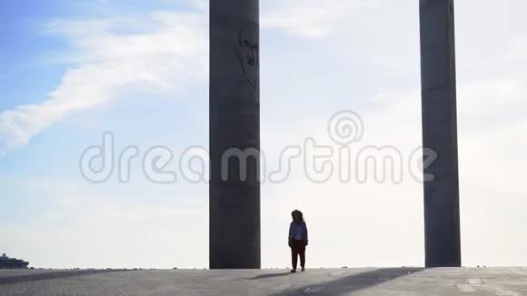 在现代公园的柱子间散步的女孩视频的预览图