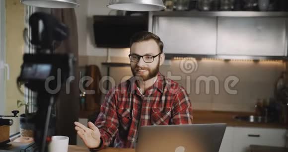快乐的年轻白种人科技博客男子为vlog制作视频与专业相机在家厨房慢动作视频的预览图