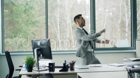 穿西装的长胡子男人独自在办公室里跳舞移动身体和手臂然后从桌子上拿文件视频的预览图