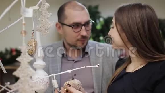 一对年轻夫妇准备圣诞节在超市里选择圣诞装饰品一个想过圣诞节的女人视频的预览图