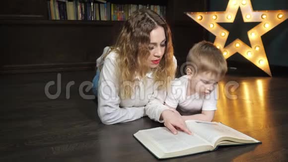年轻女子的肖像正在和她的小儿子读一本书视频的预览图